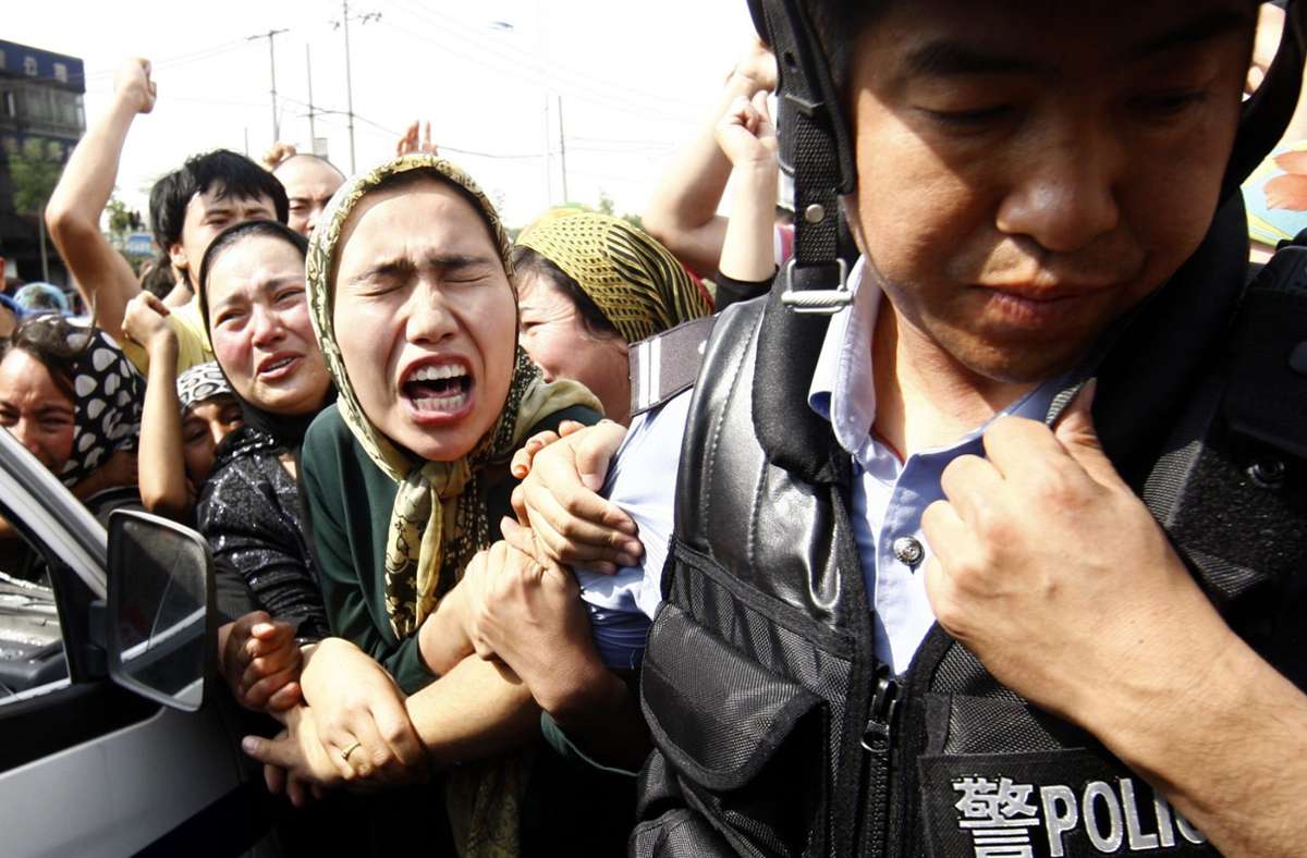 Eine Angehörige der uigurischen Minderheit in China versucht einen Polizisten zu packen währen einer Demonstration in Ürümqi (Archivfoto). Foto: picture alliance / dpa/Oliver Weiken