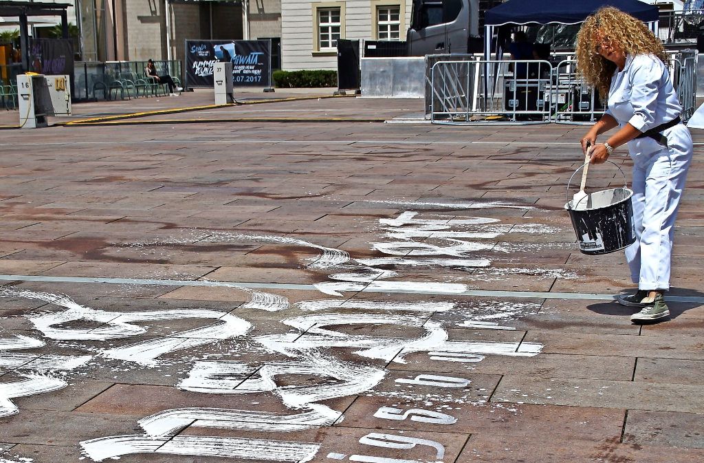 Die Kalligrafin Sigrid Artmann  malt den  Slogan vor das Rathaus. Foto: Dambacher-Schopf