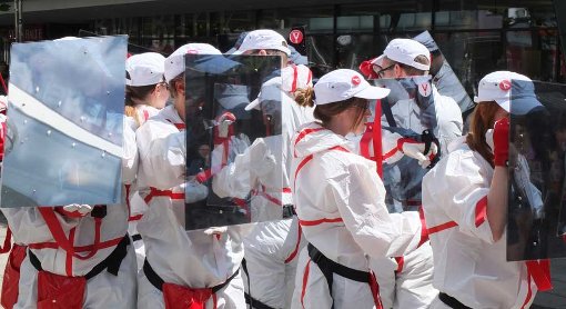 Die Teilnehmer der überwachungsfreien Tour tragen weiße Ganzkörperanzüge und ein verspiegeltes Schutzschild aus Plexiglas. Kameras können hier nicht hindurchsehen. Foto: Jan Georg Plavec