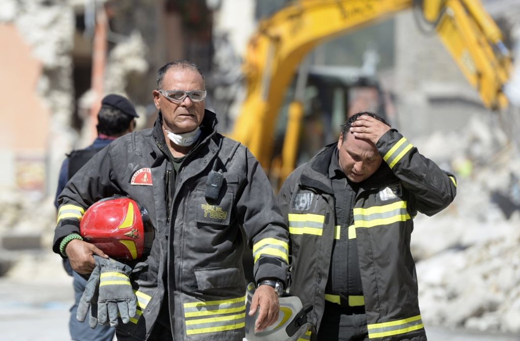 Rettungskräfte gehen am 25. August 2016 in der italienischen Stadt Amatrice an Trümmern vorbei.
