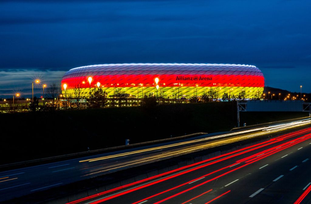 Die Münchner Allianz Arena leuchtet in den deutschen Nationalfarben Schwarz, Rot und Gold. Sie gehört in Deutschland zu den bekanntesten Bauwerken der Schweizer Architekten Jacques Herzog und Pierre de Meuron.