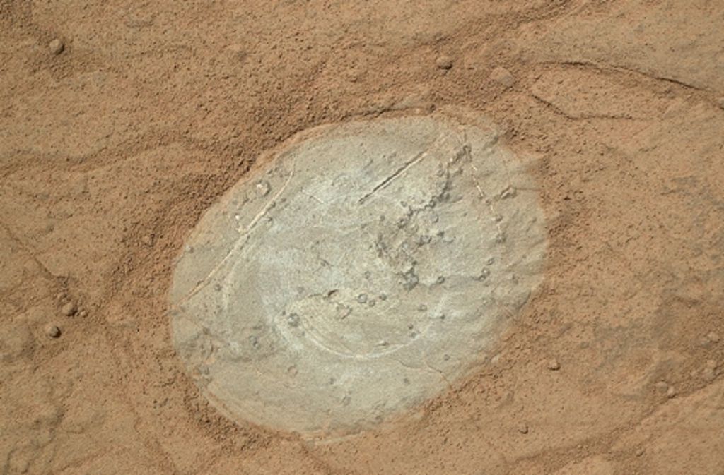Unter dem roten Staub ist das Marsgestein grau. Curiosity hat einen kleinen Fleck von einigen Zentimeter Durchmesser gebürstet und fotografiert.
