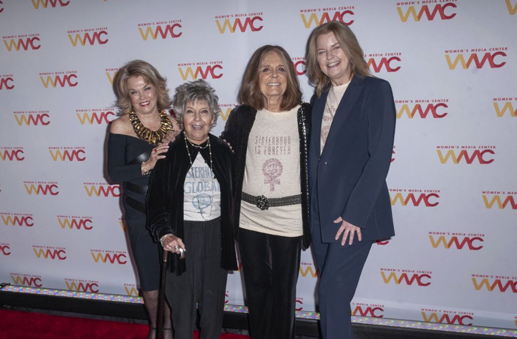 Pat Mitchell, Robin Morgan, Gloria Steinem und Julie Burton posieren vor den Kameras.