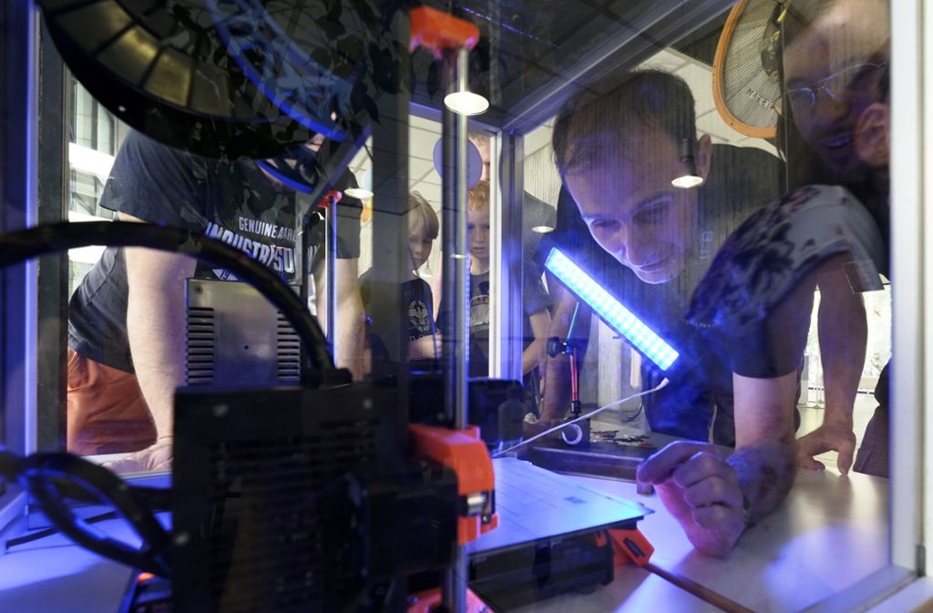 Mitarbeiter des Instituts für Flugzeugbau schauen in einen 3D-Drucker.