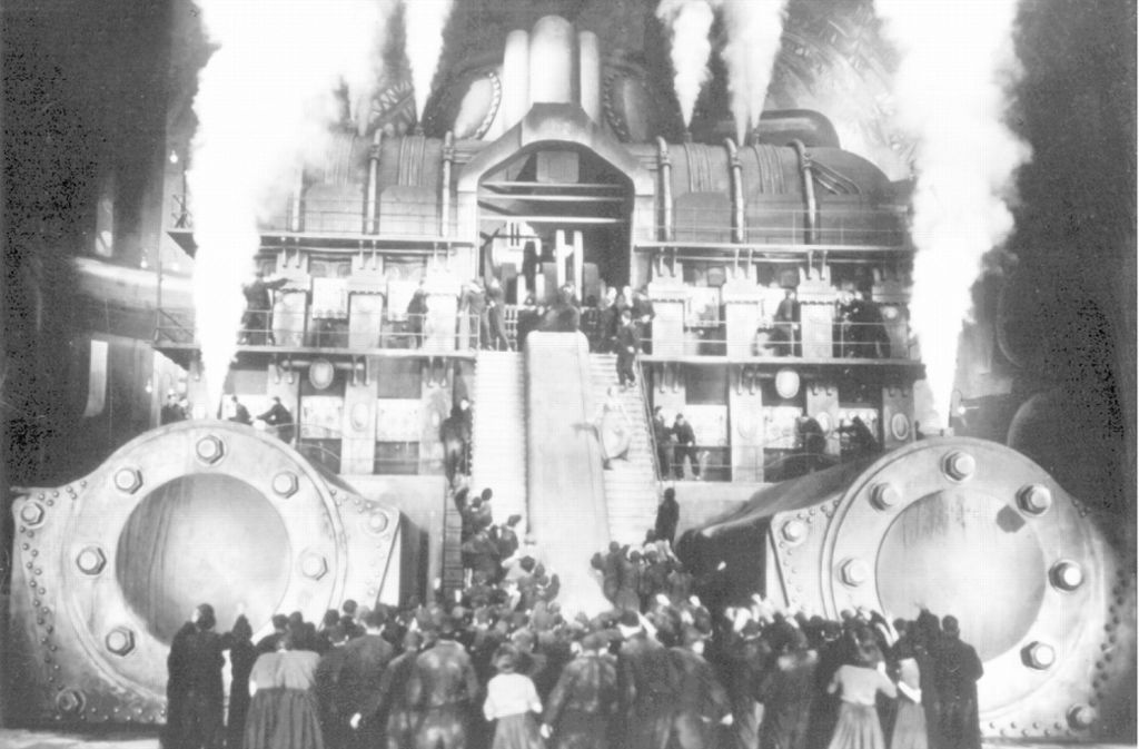 Eine aufgebrachte Menschenmenge steht vor einem dampfenden Maschinengebäude – Szene aus „Metropolis“ (Archivfoto von 1926). Der legendäre Stummfilm von Fritz Lang aus der goldenen UFA-Ära wurde 2001 als erster Film in das Unesco-Weltdokumentenerbe aufgenommen.