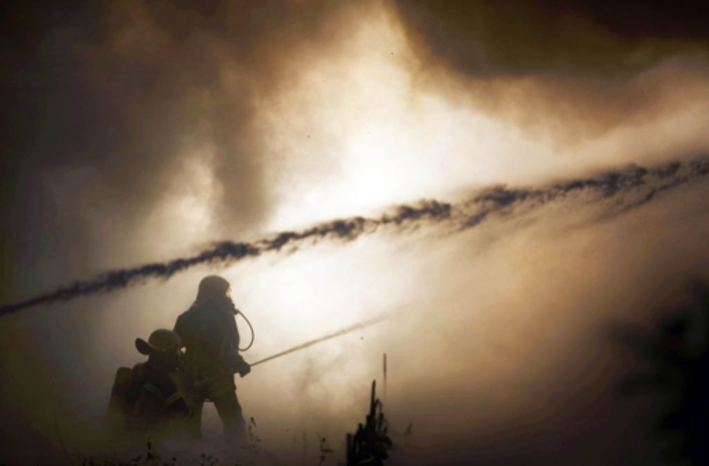 Im beißenden Qualm kämpfen Feuerwehrleute gegen die Flammen.