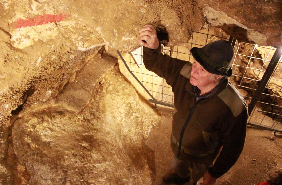 Höhlenführer Alfred Rigling verweist auf die rote Markierung. Bis hierhin war die Höhle mit Sediment befüllt, bis sie ab 1977 ausgegraben wurde.