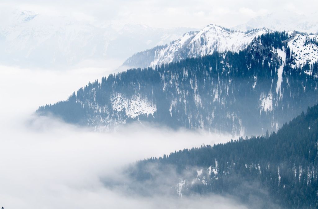 Nebel zieht durch die mit Schnee bedeckten Berge um den Wallberg in Bayern.