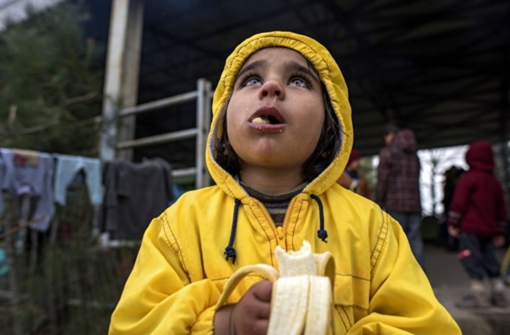 Ein Flüchtlingsmädchen isst im Zeltlager bei Idomeni eine Banane.