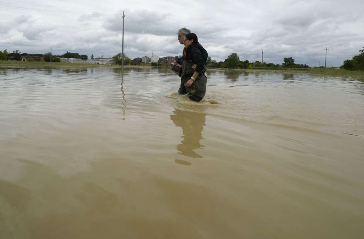Ein Paar überquert eine überflutete Straße bei der Stadt Lugo. Nach den Unwettern und Überschwemmungen in Italien ist die Anzahl der Opfer weiter gestiegen.