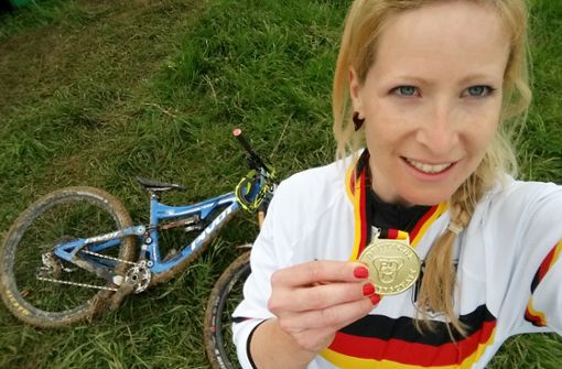 Vergoldetes Fahrkönnen bei der deutschen Meisterschaft! Bikerin Katrin Karhof hält stolz ihre Medaille in die Kamera.