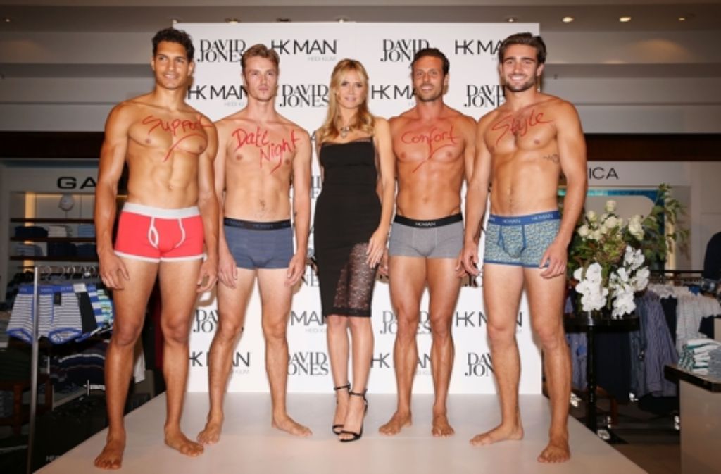 Heidi Klum umgeben von gut gebauten Männern.