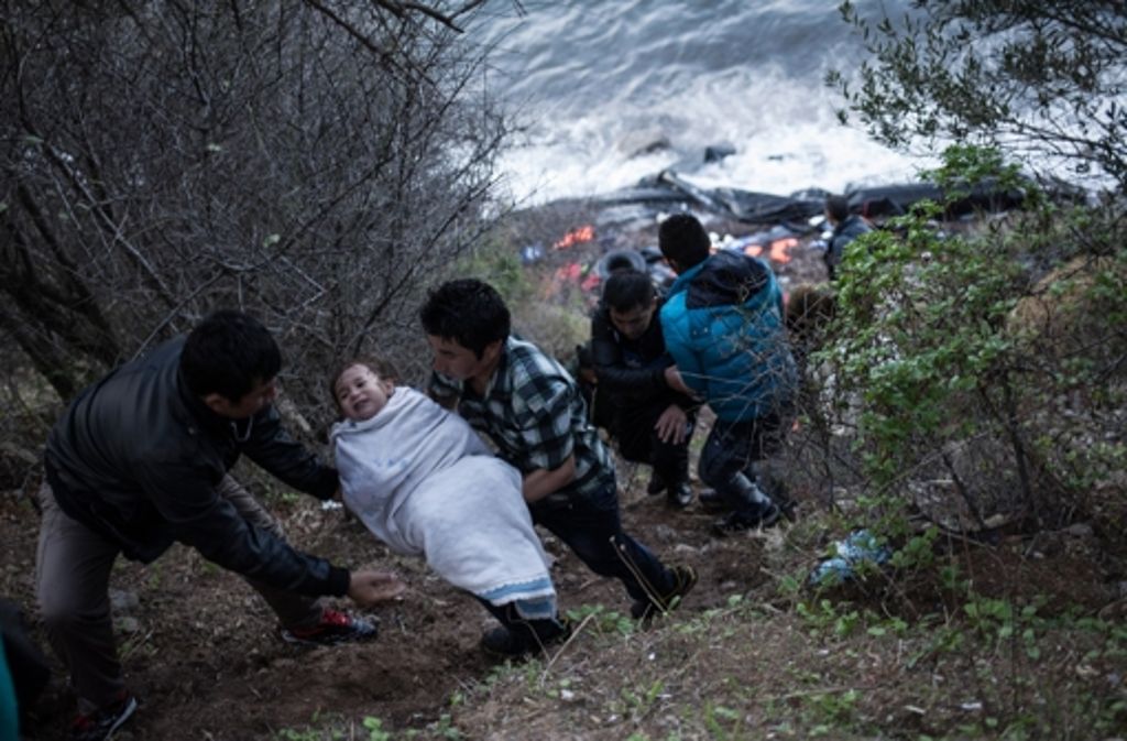 Helfer retten am 30. Oktober auf Lesbos ein Kind, nachdem es mit einem überfüllten Boot angekommen ist.