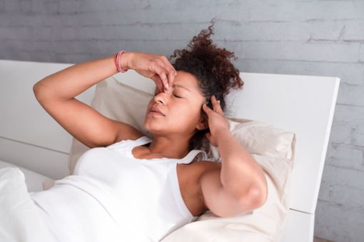 Frau im Bett mit Exploding Head Syndrome
