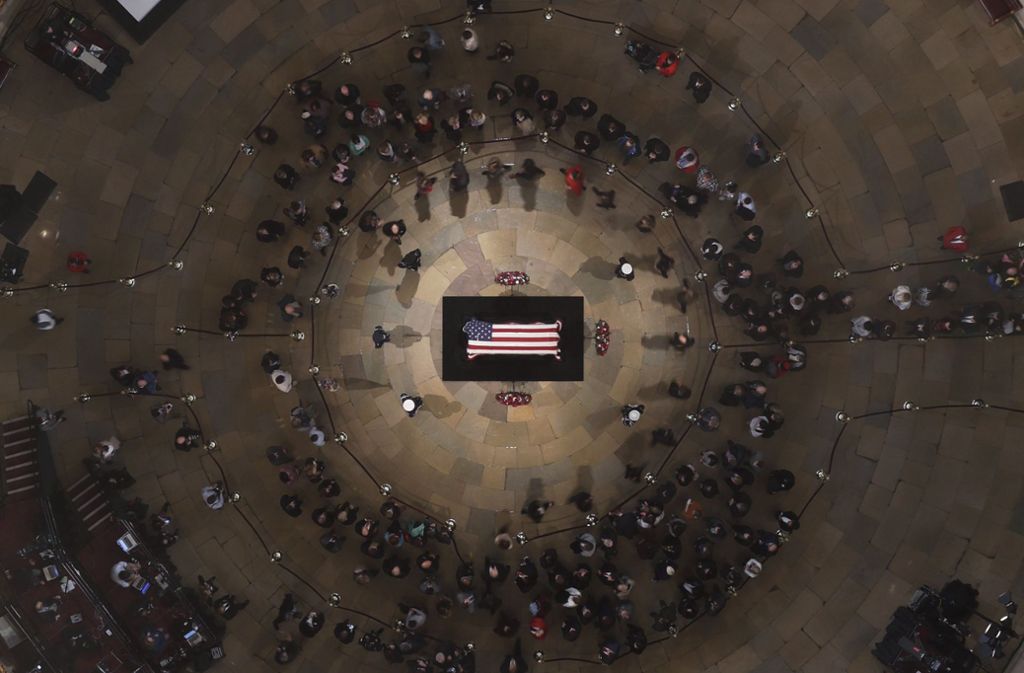 Menschen stehen um den mit einer Fahne verhüllten Sarg des ehemaligen US-Präsidenten George H.W. Bush herum, der in der Rotunde des U.S. Kapitols aufgebahrt ist.