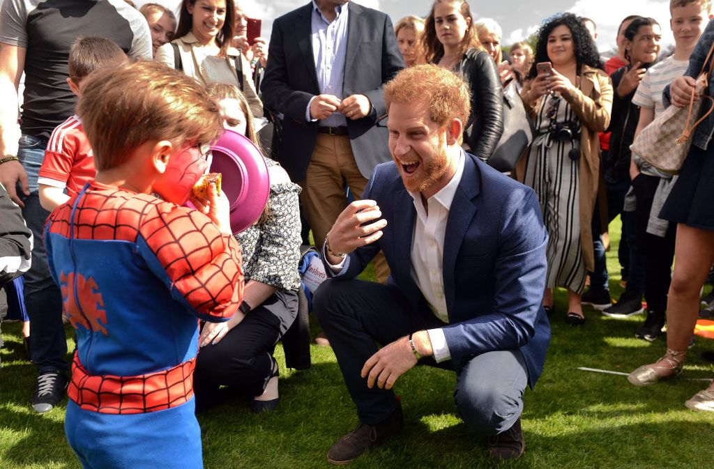 Prinz Harry scherzt mit einem kleinen Jungen, der ein Spiderman-Kostüm auf der Gartenparty trägt.