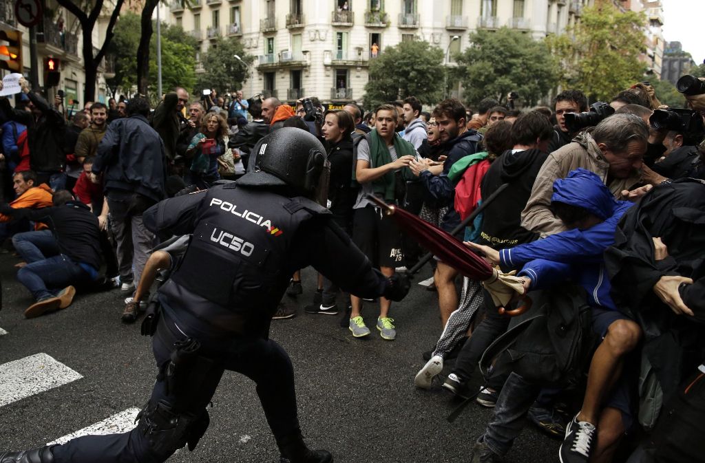 Ein spanischer Nationalpolizist geht mit seinem Schlagstock auf Befürworter des Referendums los.