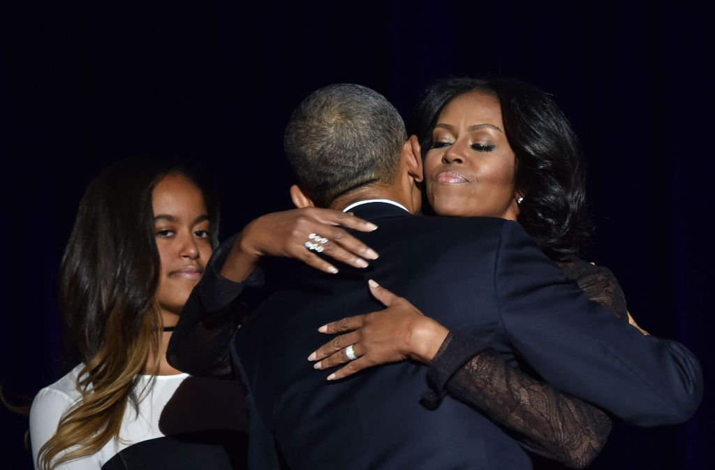 Michelle und ihr Ehemann drücken sich innig – dieses Foto ist auf der Abschiedsrede Obamas am 10. Januar 2017 in Chicago enstanden. Links ist Malia, eine der beiden Töchter des Präsidentenpaares, zu sehen.