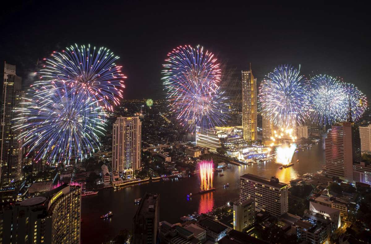 Thailand, Bangkok: Feuerwerkskörper explodieren über dem Chao Phraya Fluss während der Neujahrsfeierlichkeiten.