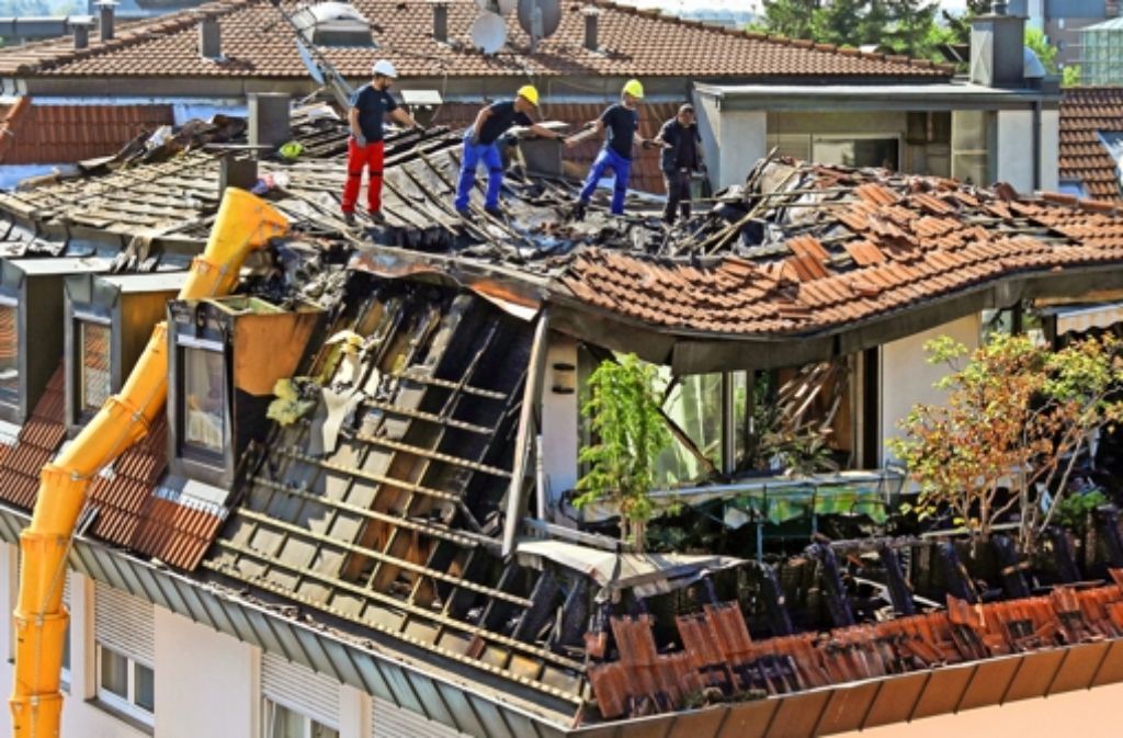 Die Aufräumtruppe deckt das Dach des zerstörten Hauses ab (oben). Das Feuer wurde wohl im Innenhof unter einer Treppe entfacht.