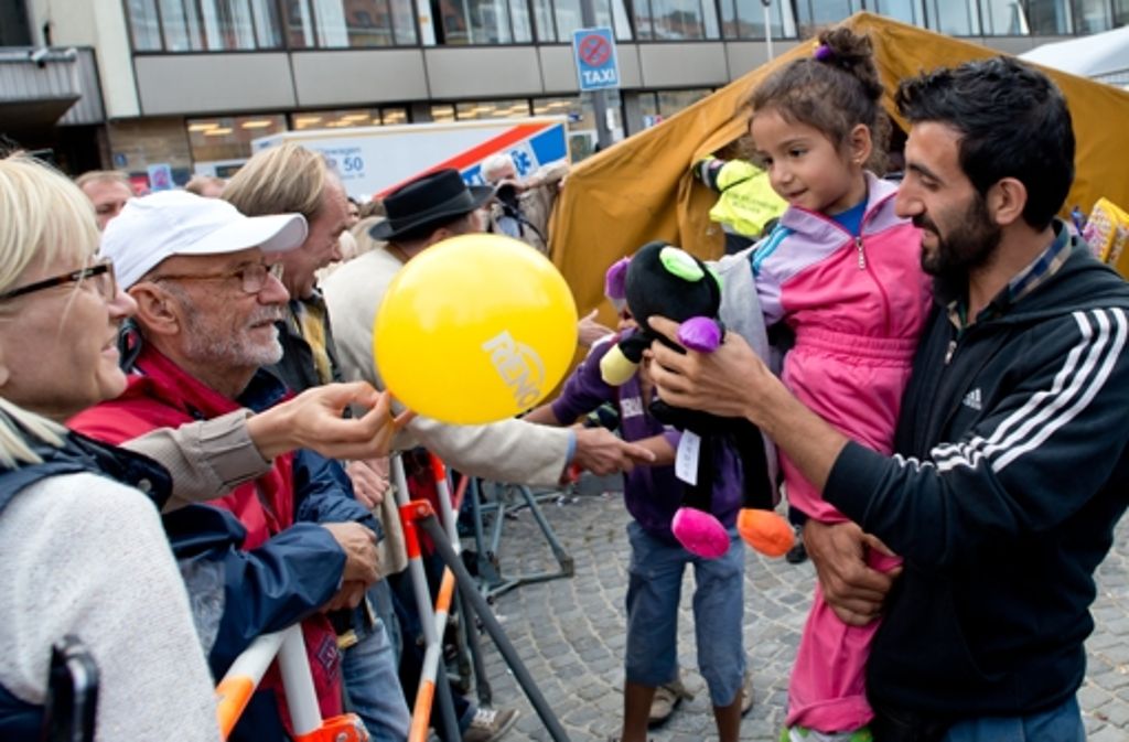 München: Passanten überreichen einem kleinen Mädchen Luftballons und Kuscheltiere.