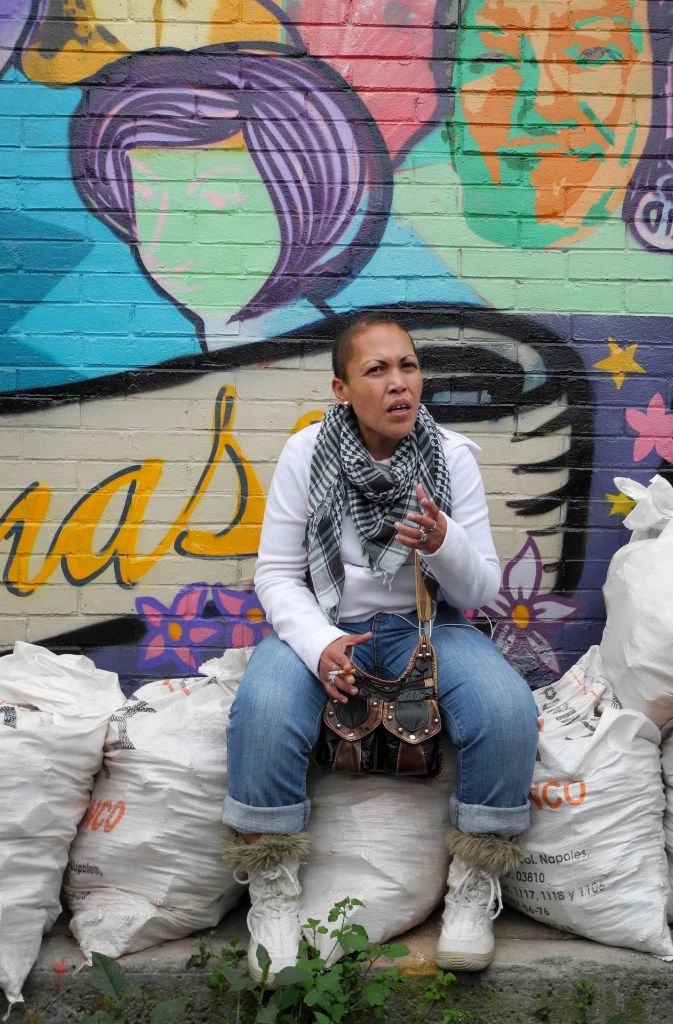 Mayra Valenzuela Rosas sitzt vor einem Wandgemälde zu Ehren der „Siete Cabronas“ (Sieben Teufelsweiber).