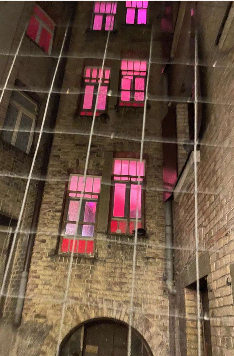 Im Nachbargebäude leuchtet das Treppenhaus des Bordells rot.