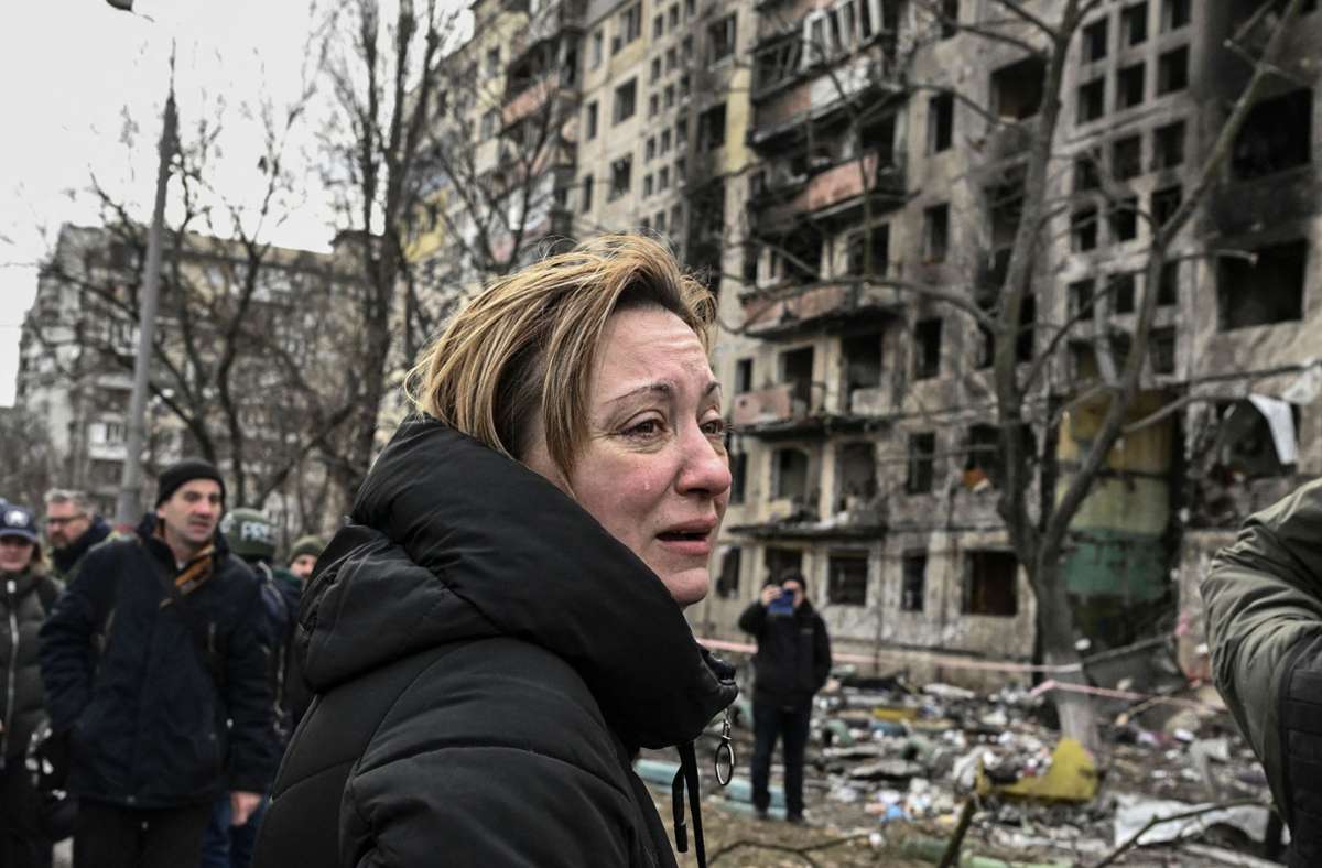 Eine weinende Frau vor einem nach Beschüssen zerstörten Gebäude im Stadtteil Obolon in Kiew