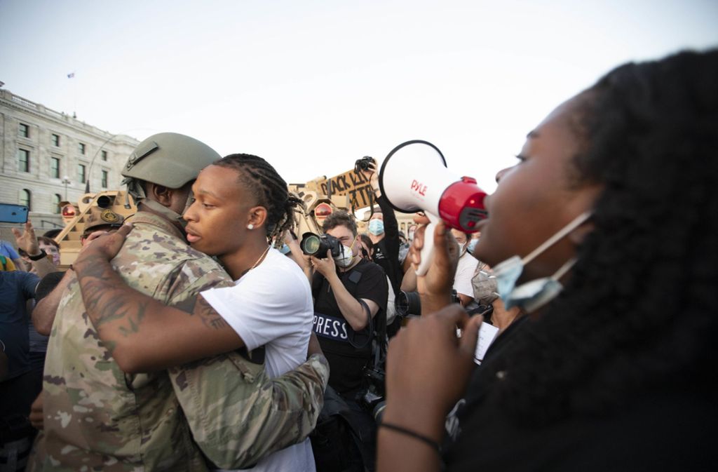 Acie Matthews Jr., der Gleichberechtigungsbeauftragte der Nationalgarde von Minnesota, umarmt einen Mann, nachdem er mit den Demonstranten gebetet hat.