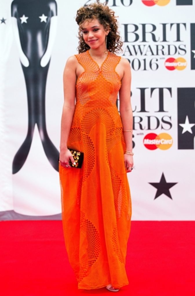 ...sondern auch die britische Sängerin Izzy Bizu. Das orange Kleid tut nicht nur durch seine Farbe in den Augen weh, es sieht eher aus wie ein oranges Fischernetz.