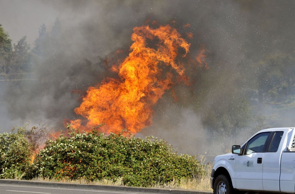Das Feuer bedroht Häuser, Autos und Menschen.