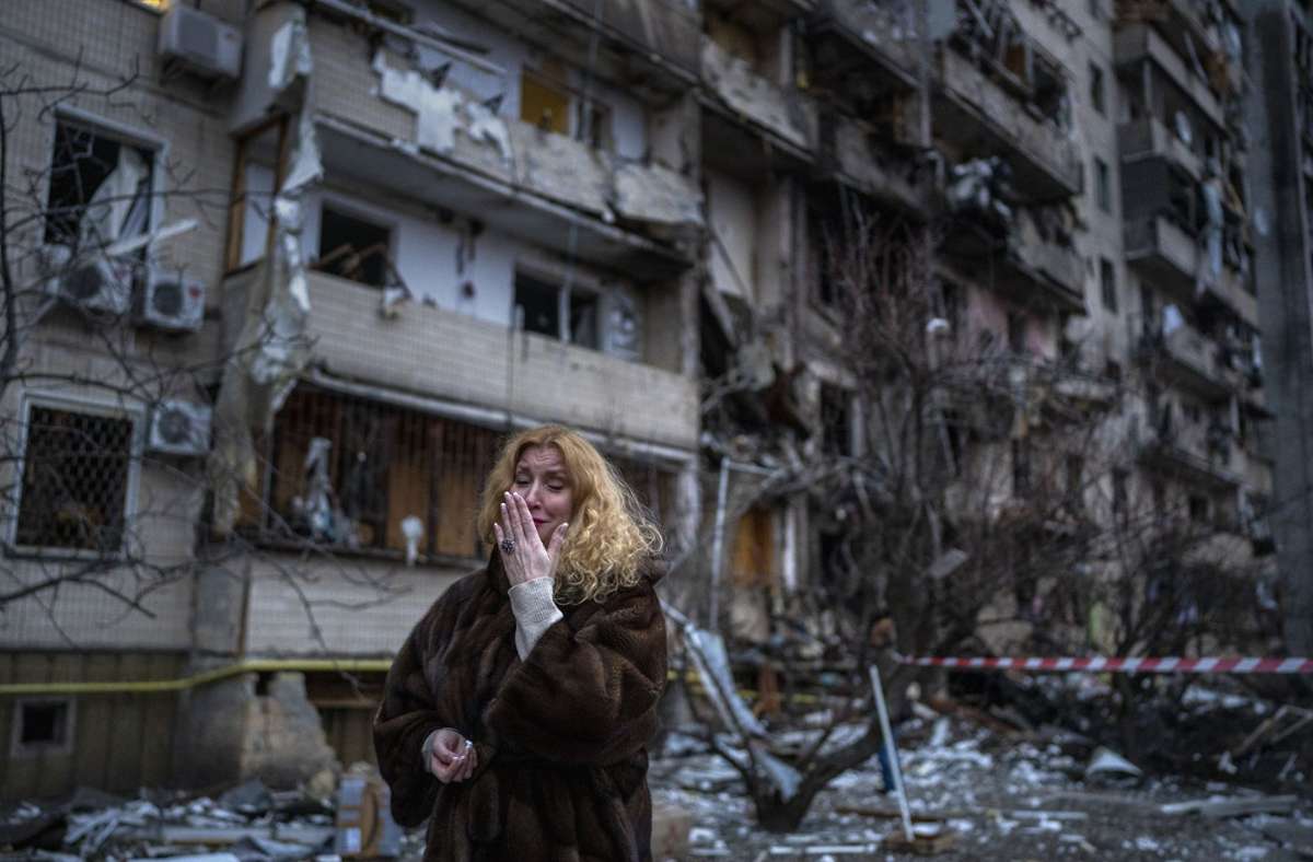Eine Ukrainerin steht neben einem Haus, das bei einem Raketenangriff zerstört wurde.