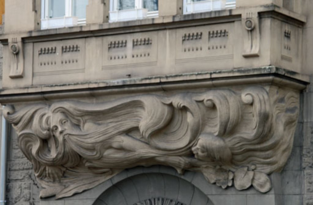 Über dem Eingang eine große Neptunfigur mit wallendem Bart und einer kleinen Nixe rechts unten.