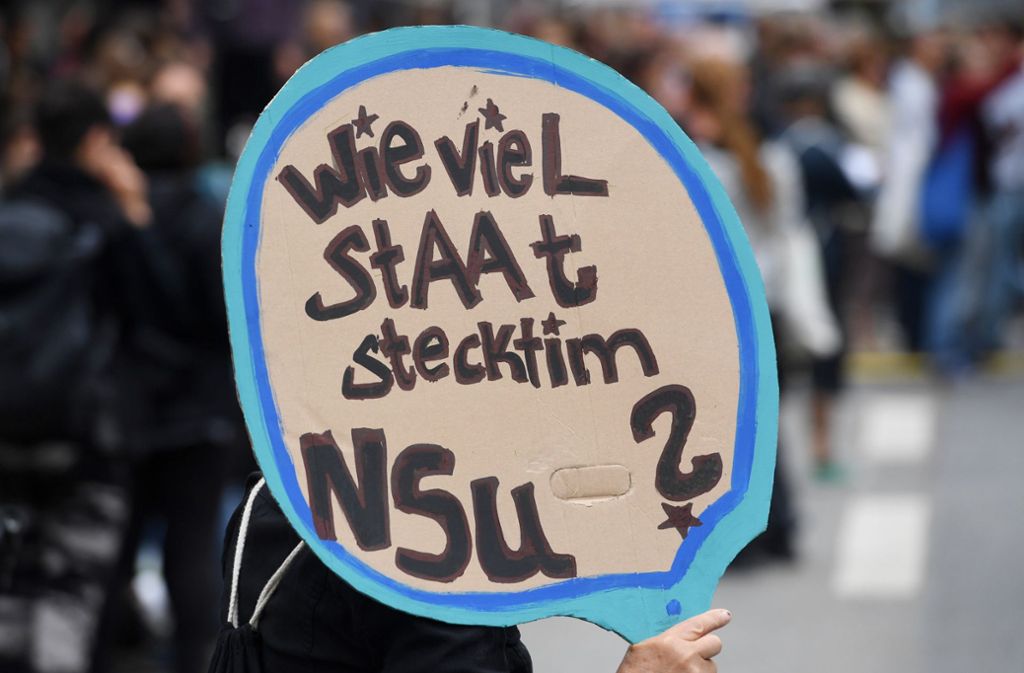 Demonstranten halten bei einer Kundgebung vor dem Oberlandesgericht ein Schild mit der Aufschrift „Wieviel Staat steckt im NSU?“.