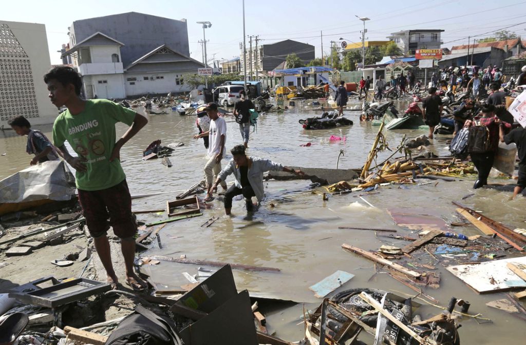 Menschen stehen in Palu, Zentral-Sulawesi in Trümmern.