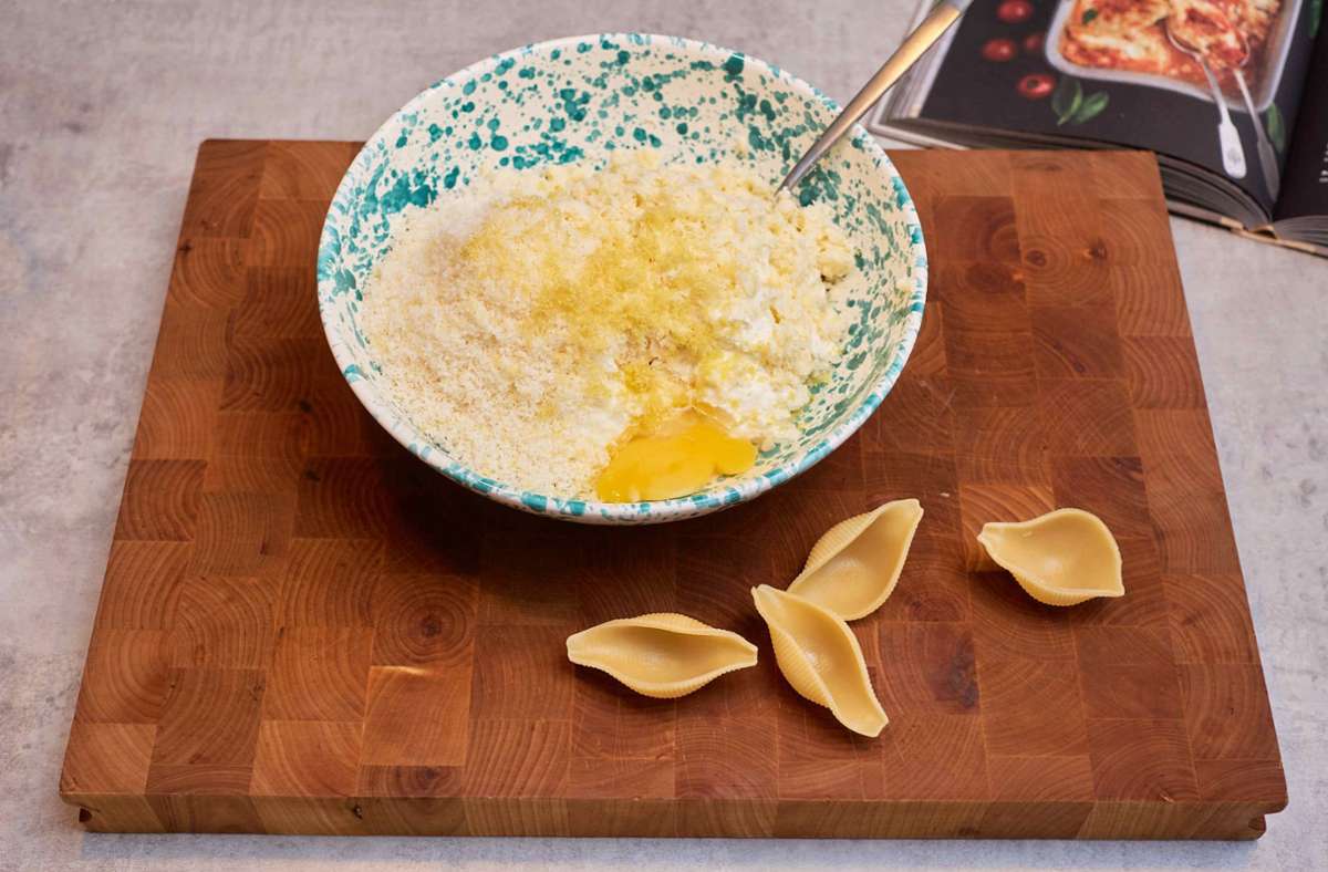 In einer kleinen Schüssel vermengt man den Ricotta mit dem Parmesan, dem Mozzarella, dem Zitronenabrieb und dem Ei zu einer einheitlichen Masse und würzt sie mit Salz und Pfeffer.