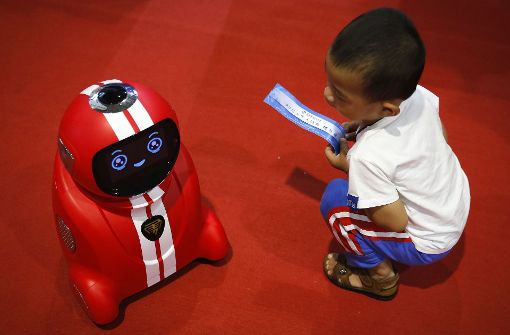 Wer lernt hier von wem? Ein Kind beobachtet während der Welt-Roboter-Konferenz in Peking (China) einen selbstlernenden Roboter. Foto: AP