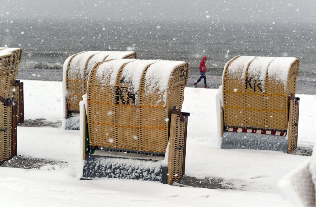 Burgtiefe auf Fehmarn: Urlauber gehen durch das Schneetreiben am Südstrand an der Ostsee.
