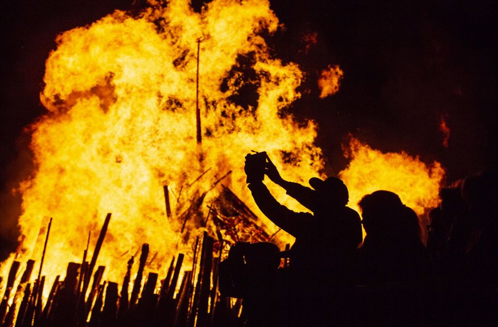 Ein Zuschauer fotografiert das Maifeuer bei der Walpurgisnacht in Erfurt