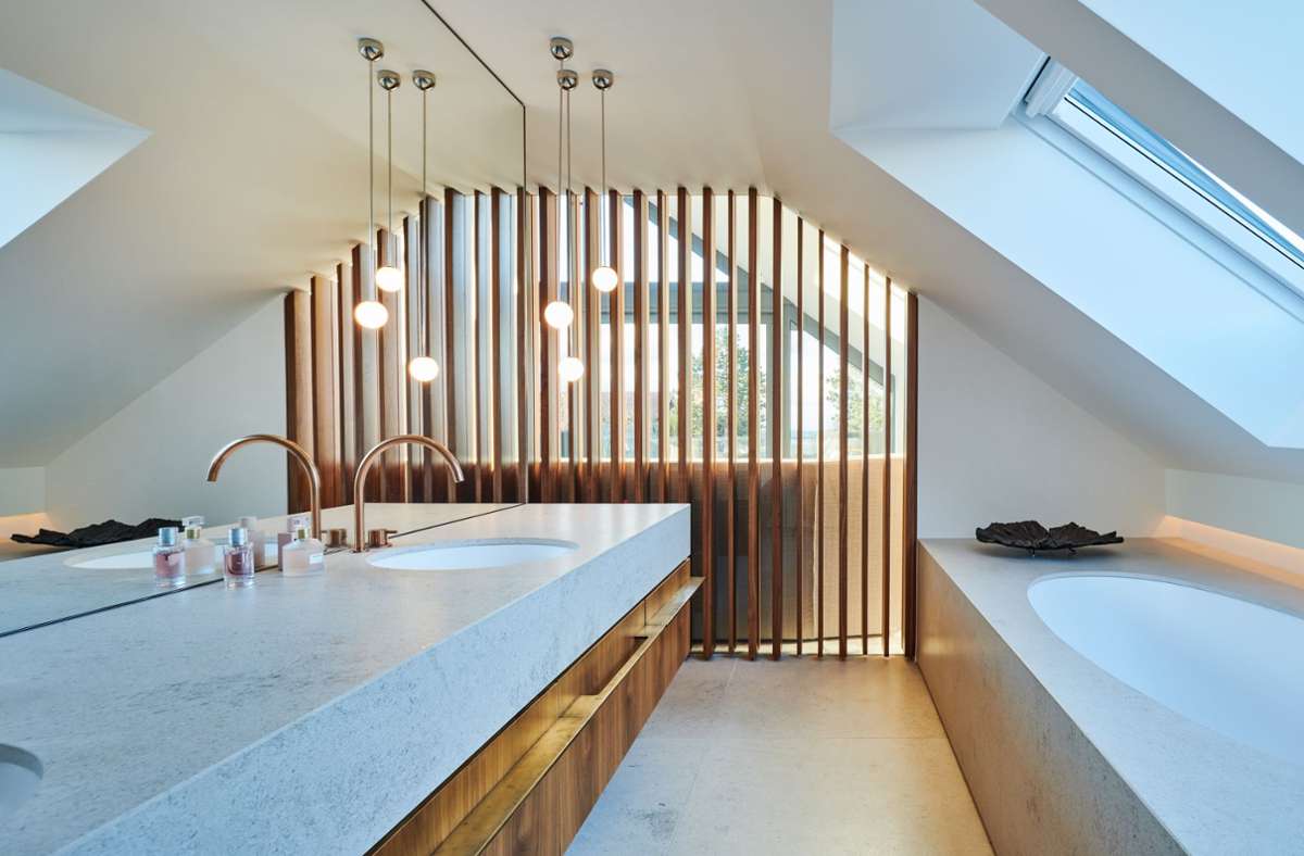Badezimmer im Obergeschoss. Die Badewanne ist unter der Schräge gut platziert. Die Verglasung mit Holzlamellen bietet einen Blick ins Schlafzimmer.