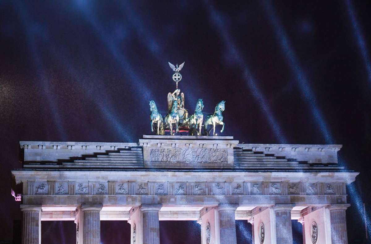 Berlin: Lichstrahlen leuchten vor dem dunklen Himmel und der Quadriga bei der Silvesterfeier vom ZDF am Brandenburger Tor.