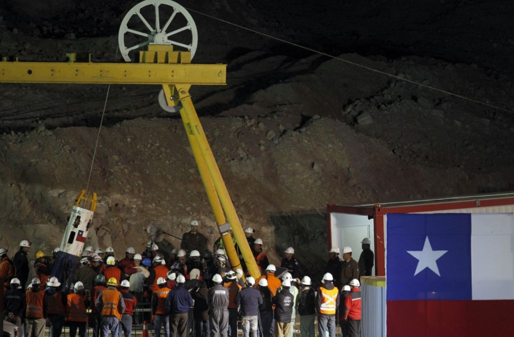 San José, Chile, 13. Oktober 2010: Präsident Sebastian Pinera und viele andere sind dabei, als der Minenarbeiter Carlos Mamani Solis nach 69 Tagen in 700 Metern Tiefe in einer Rettungskapsel zurück an die Erdoberfläche geholt wird. Insgesamt werden 33 verschüttete Bergleute gerettet