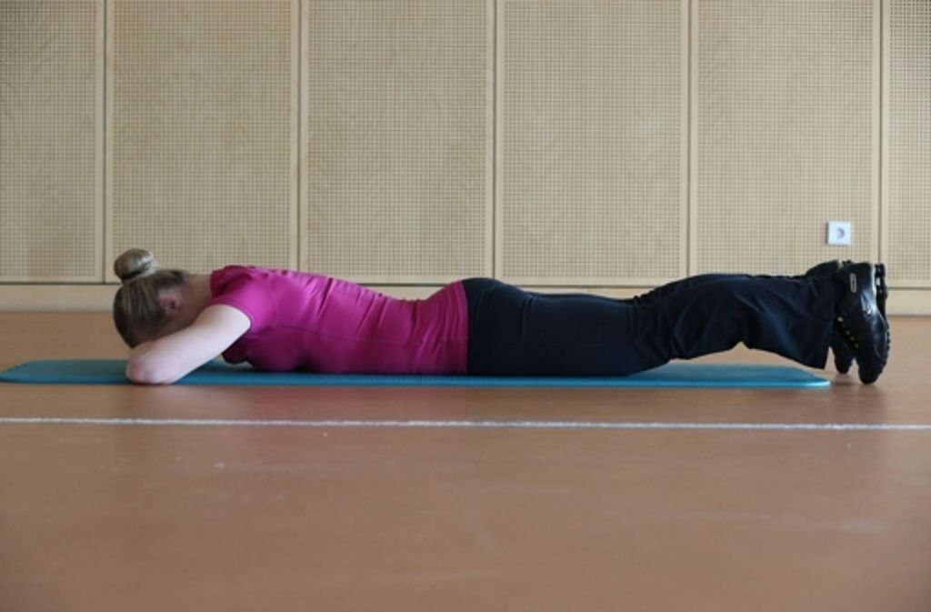In Bauchlage auf die Matte legen und die Zehenspitzen aufstellen. Im Körper eine Grundspannung erzeugen.