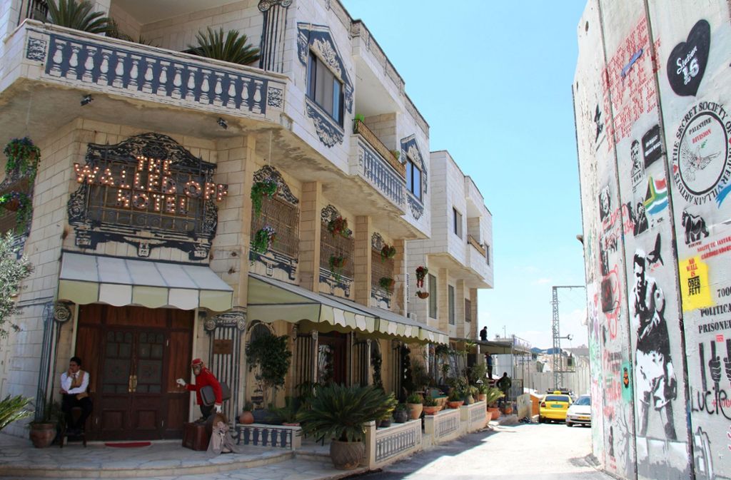 Banksy betreit in der Westbank in den Palästinensergebieten ein Hotel. Es sei das Hotel mit dem hässlichsten Ausblick der Welt, verspricht der Künstler.