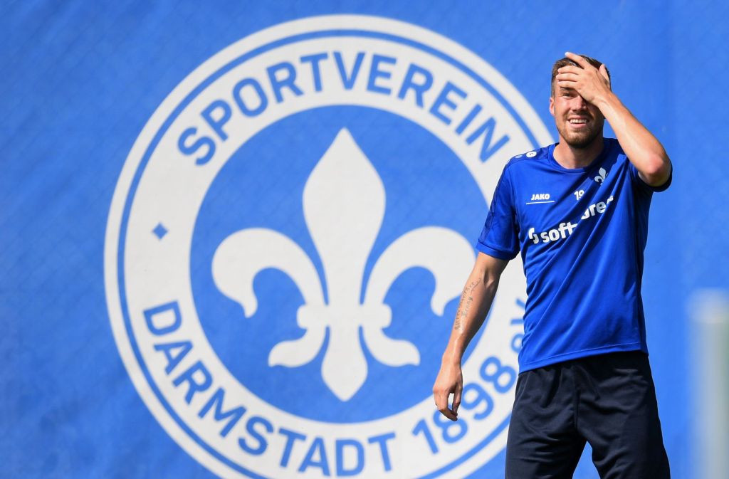 Darmstadt 98 ist abgestiegen und spielt nun in der 2. Bundesliga. Kevin Großkreuz steht vor dem Wappen seines neuen Vereins.