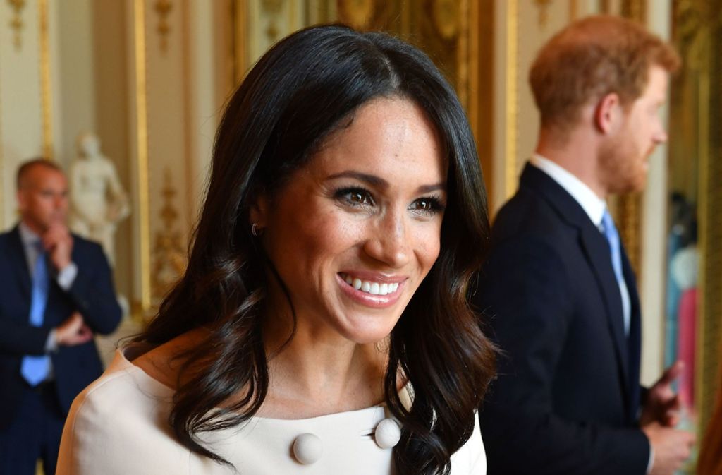 Lächeln, Hände schütteln, Smalltalken: Herzogin Meghan bei einem Empfang im Buckingham Palace. Im Hintergrund: Ihr Mann, Prinz Harry.