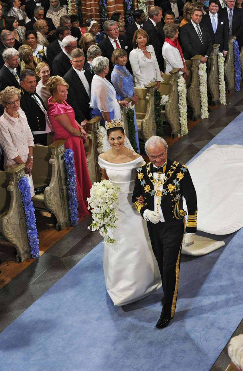 In einem klassisch eleganten Brautkleid des schwedischen Modeschöpfers Pär Engsheden schreitet Victoria am Arm ihres Vaters in den Stockholmer Dom.
