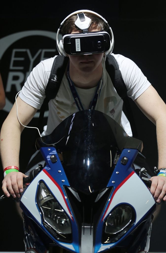 Ein Fachbesucher unternimmt mit der VR-Brille von Gear VR von Samsung eine dreidimensionale Motorradfahrt.