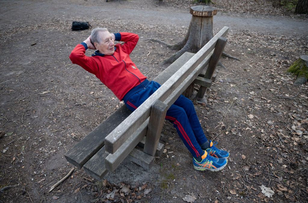 Kurz vor dem Start macht er Liegestütze und Bauchmuskelübungen an einer Holzbank auf dem Waldparkplatz.