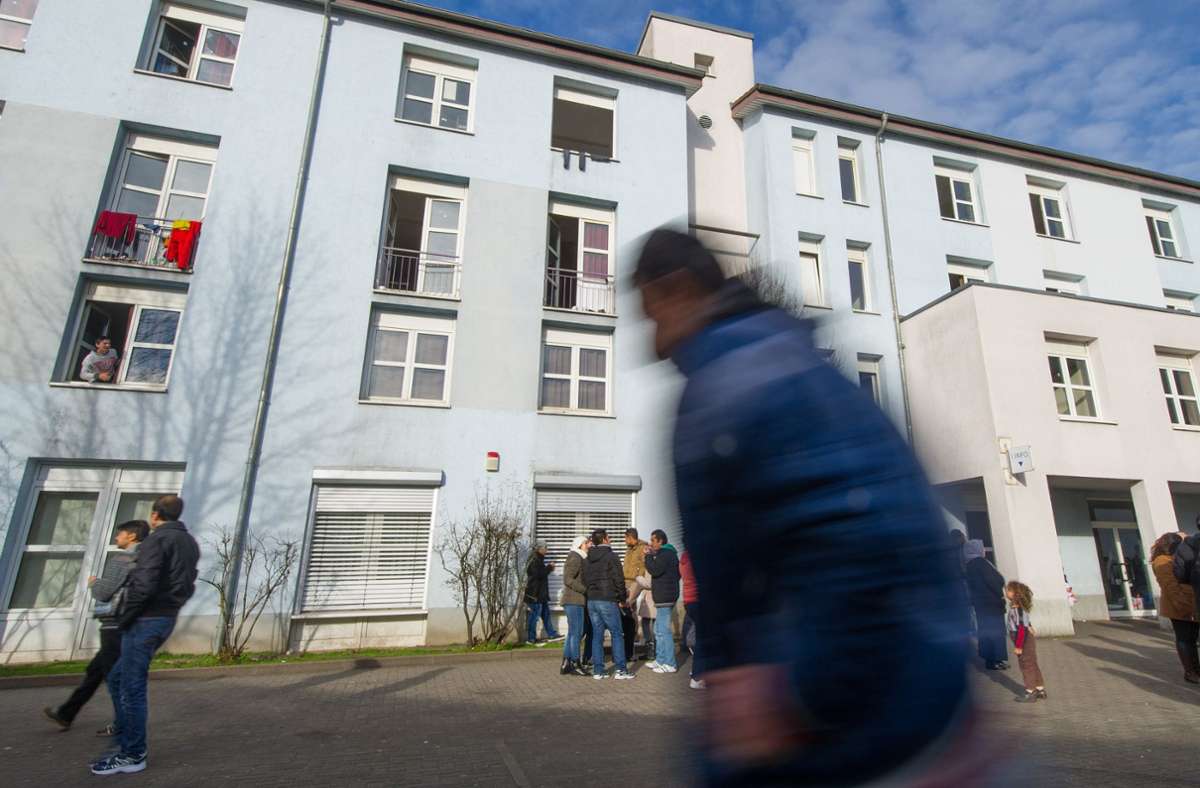 Asylbewerber sind am 15. 1. 2014 in Karlsruhe in der Landeserstaufnahmeeinrichtung vor einem Unterkunftsgebäude zu sehen.